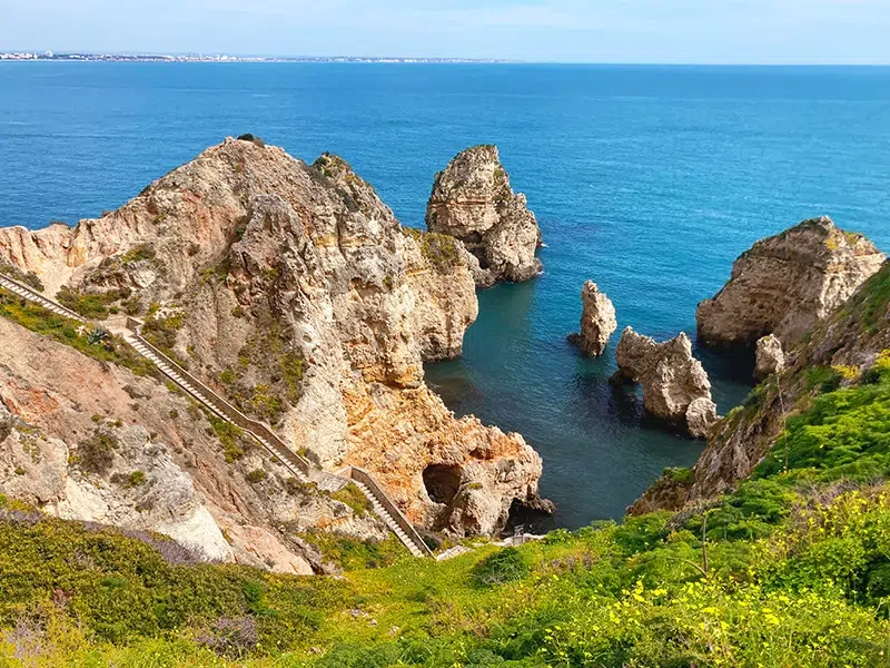 Lagos Piedade Cliffs Arches 4 Stairs blue sea view with hill and greenery
